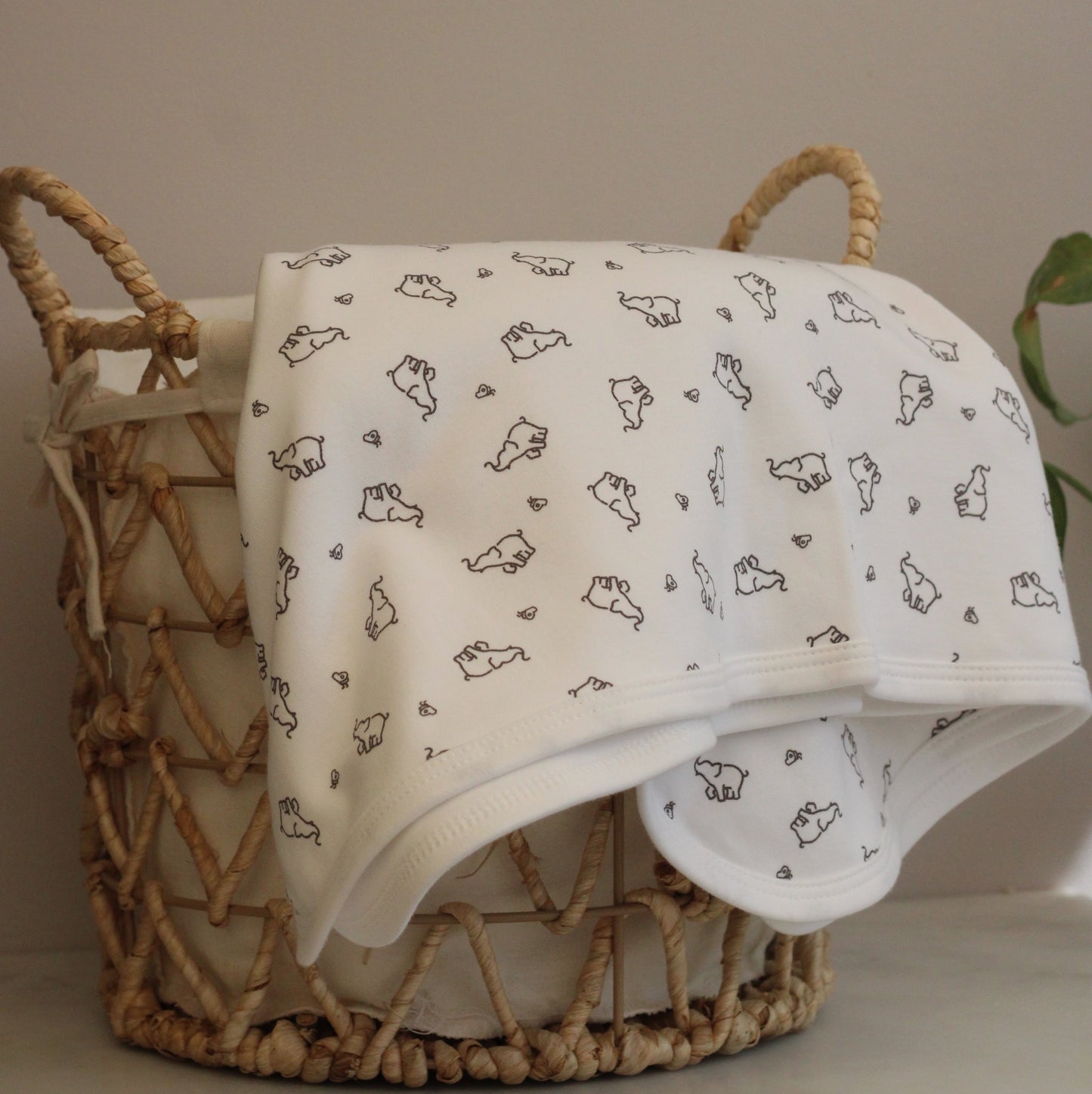 white elephant and butterfly baby blanket. super soft 100% organic cotton, GOTs certified in a wicker basket.